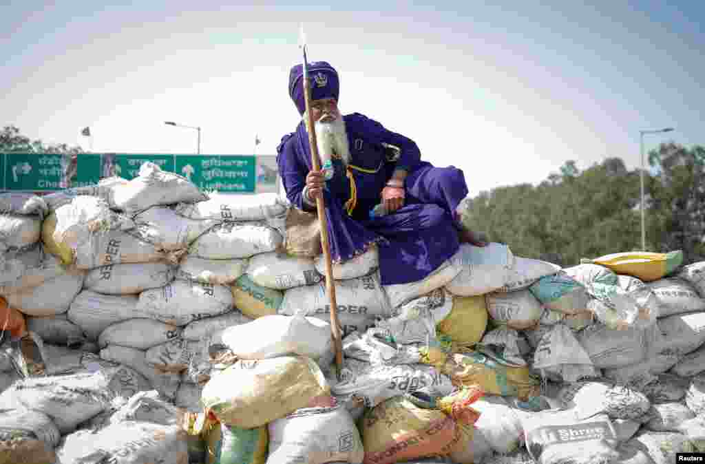 A Nihang, or Sikh warrior, rests on a makeshift barricade of sand bags at a protest site during the march toward New Delhi to push for better crop prices, at Shambhu Barrier, the border between Punjab and Haryana states, India.