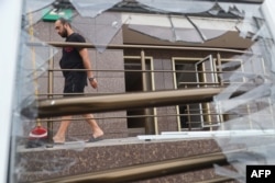 Čovek prolazi pored razbijenog prozora na stambenoj zgradi oštećenoj u ruskom raketnom udaru na Odesu, 19. jula 2023.