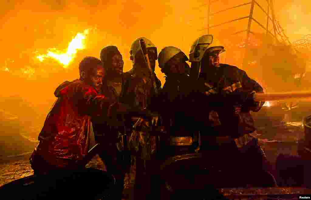Firefighters and volunteers extinguish a fire that broke out at a commercial depot, used for oil barrels and flammable drums, near Muthurwa settlement, in Nairobi, Kenya, Jan. 30, 2024.