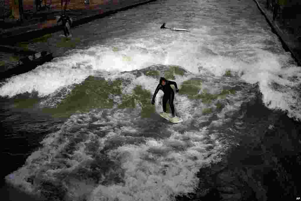 A surfer rides on an artificial wave in the river 'Eisbach' at the 'Englischer Garten' (English Garden) downtown in Munich, Germany.