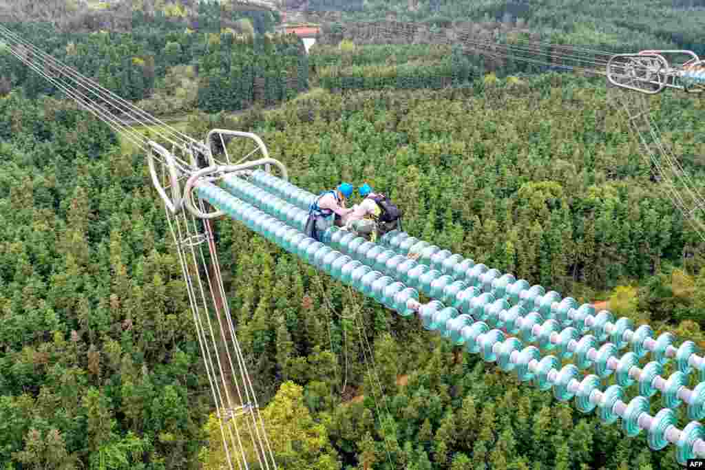 Workers fix cables on a transmission tower in Yichun, in central China's Jiangxi province.