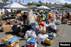 Los estibadores en Hawái y otros voluntarios preparan donaciones para las víctimas de los incendios forestales de Maui en el Muelle 1, donde las enviarán a Maui la próxima semana, en Honolulu, Hawái, el 12 de agosto de 2023.