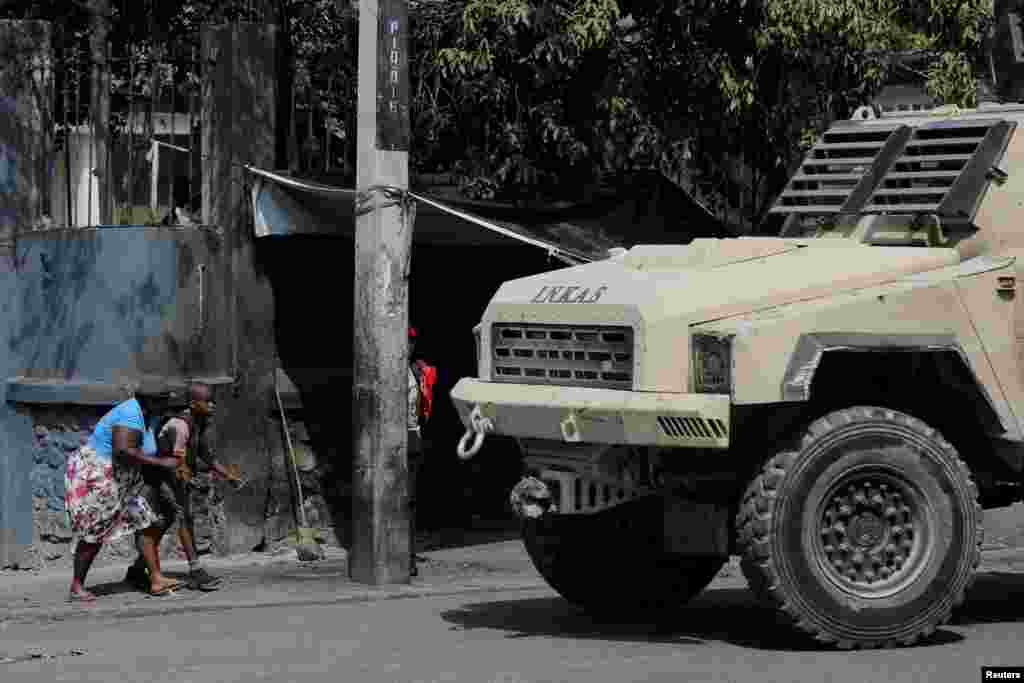 A woman and a child duck near a police vehicle after leaving school amid gang violence in Port-au-Prince, Haiti, March 3, 2023.