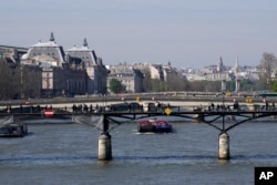 FILE - Barges travel along the River Seine in Paris, Wednesday, April 5, 2023. (AP Photo/Christophe Ena)