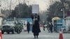 Mlada žena protestuje sama protiv talibanske zabrane visokog obrazovanja žena, ispred Kabulskog univerziteta, dok talibanski stražari stoje u blizini, u Kabulu, Afganistan, 25. decembar 2022.