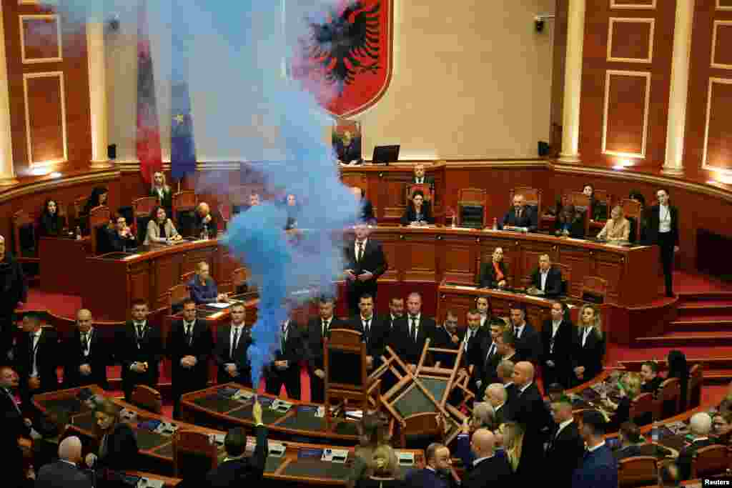A member of parliament from the Democratic Party, Albania's biggest opposition party, sets off a smoke flare as the parliament gathers for a vote on whether to lift the immunity of opposition leader Sali Berisha so he can face corruption charges, in Tirana.