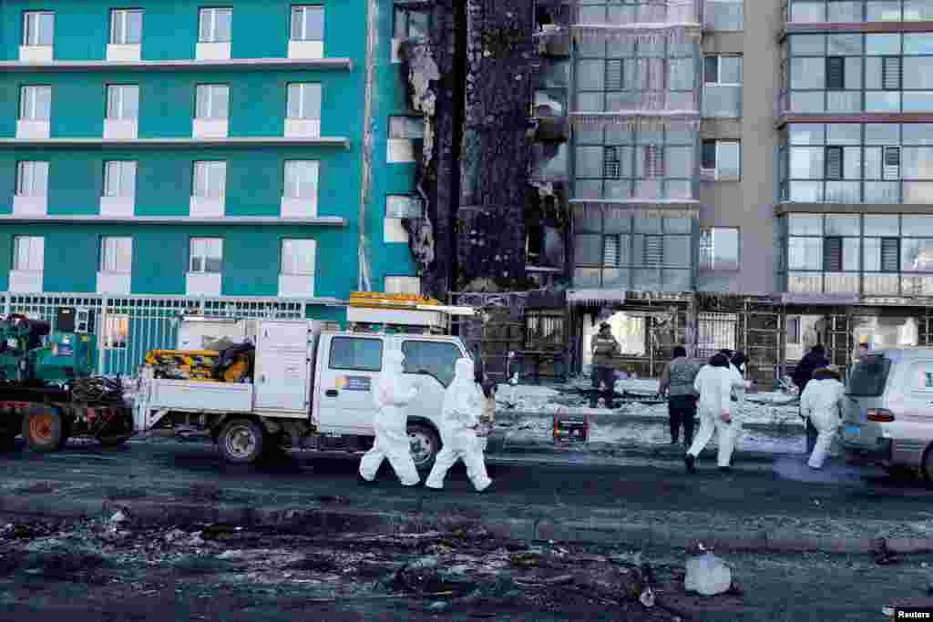Experts in PPE walk to a building damaged by an explosion after a truck carrying liquefied natural gas crashed, in Ulaanbaatar, Mongolia.