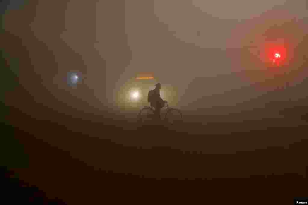 A man rides a bicycle amidst heavy fog in New Delhi, India.