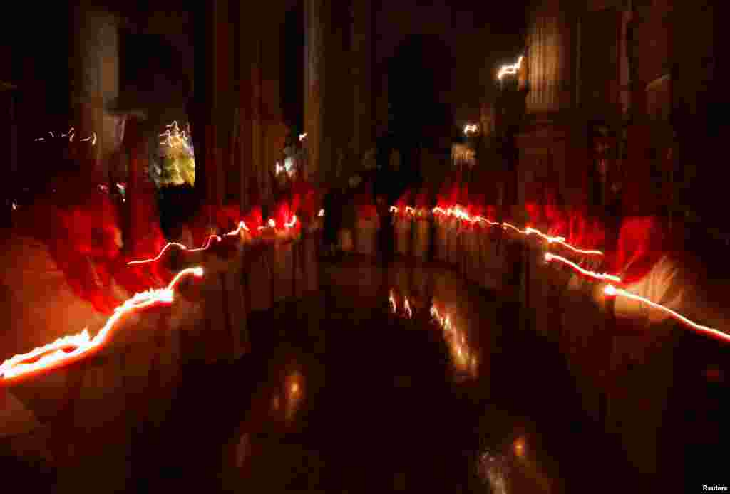 Penitents hold candles as they take part in a penitence act inside a church during the Holy Week in Ronda, Spain, March 27, 2024.