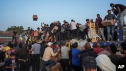 Warga Palestina menyerbu truk berisi bantuan kemanusiaan yang dibawa melalui dermaga baru yang dibangun AS, di Jalur Gaza tengah, Sabtu, 18 Mei 2024. (Foto: Abdel Kareem Hana/AP Photo)