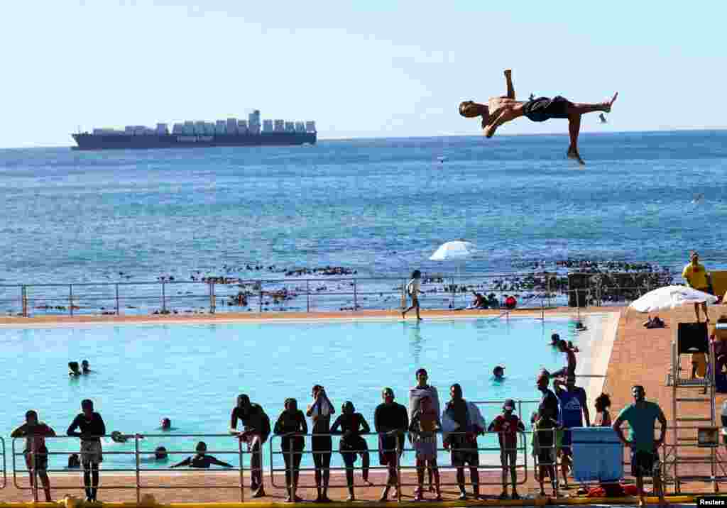 A person dives from a springboard during a hot summer day at Sea Point swimming pool in Cape Town, South Africa.