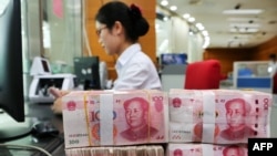 中国江苏省南通市的一家银行的一名员工处理100元纸币。资料图片，2018年7月23日。