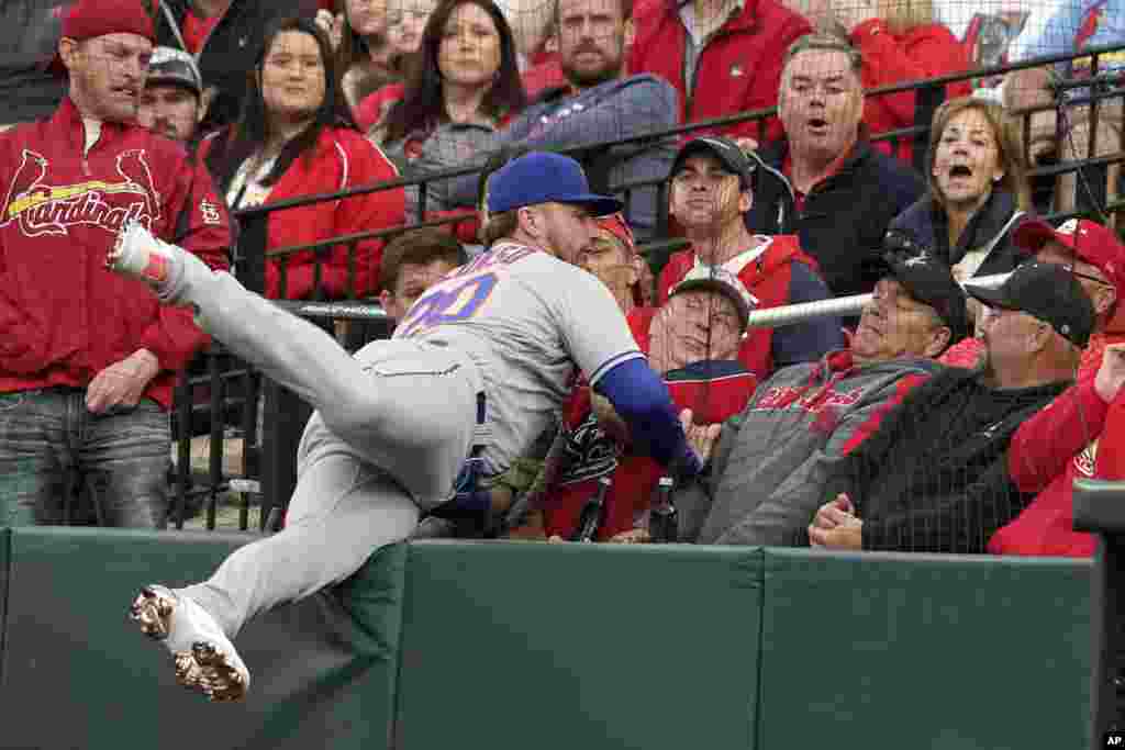 New York Mets first baseman Pete Alonso falls against netting as he catches a foul ball by St. Louis Cardinals' Paul Goldschmidt for an out during the first inning of a baseball game, April 25, 2022, in St. Louis, Missouri.