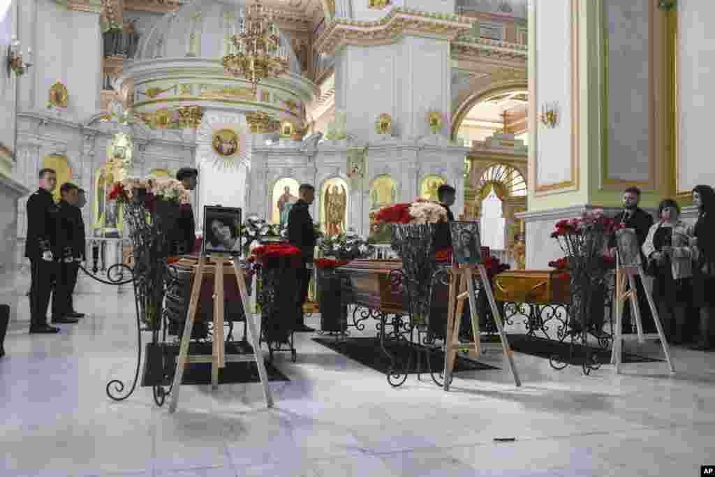 Portraits are placed next to coffins of from right, Kira Glodan, three-month-old, her mother Valerya Glodan, 28, and grandmother Lyudmila Yavkina, 54, killed in their apartment by shelling, during a funeral ceremony at the Transfiguration Cathedral in Odesa, Ukraine.
