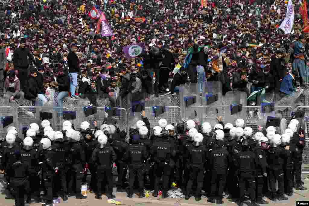 Police officers stand guard as supporters of pro-Kurdish Peoples' Democratic Party (HDP) gather to celebrate Nowruz, which marks the arrival of spring, in Diyarbakir, Turkey.