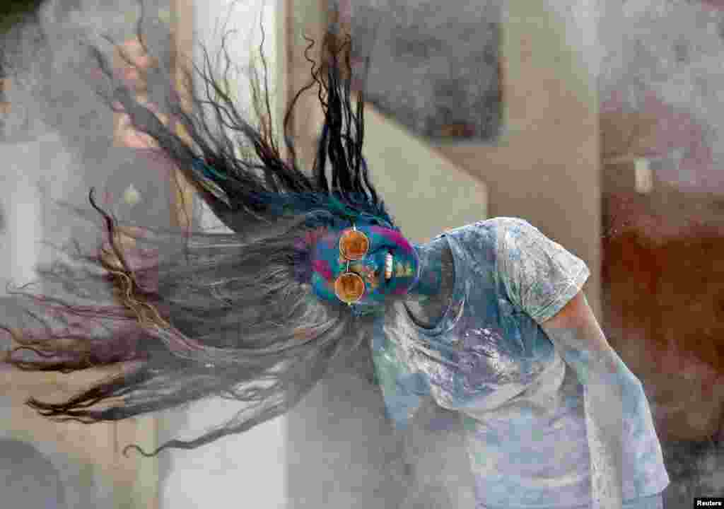 A woman shakes her head to remove the colored powder during Holi celebrations in Ahmedabad, India.