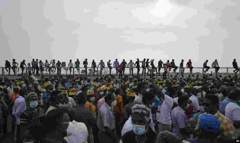 Supporters of Sri Lanka's main opposition sit on the fence of the Chinese-owned Port City project as they gather to protest outside the president's office in Colombo. The protesters were demanding the resignation of President Gotabaya Rajapaksa, as the country suffers one of the worst economic crises in its history.