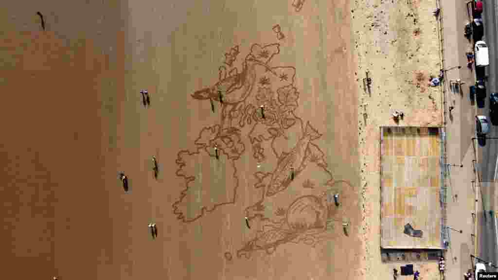 People walk past a huge sand drawing on South Bay Beach, created by Sand in Your Eyes, to alert people to the loss of wildlife, in Scarborough, Britain, March 23, 2022.