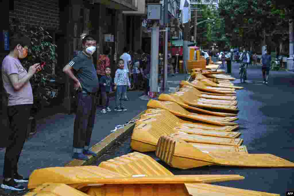 People stand next to barriers taken down earlier in the afternoon in the Jing' an district of Shanghai, China, as the city prepares to lift more curbs after two months of heavy-handed restrictions.
