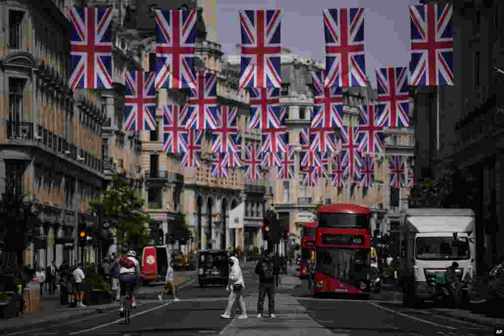People cross the Regent Street shopping district with Union flags hanging over it to mark the upcoming Platinum Jubilee of the 70 year reign of Britain's Queen Elizabeth II, in London.