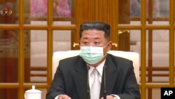 朝鲜领导人金正恩5月12日戴着口罩出席一次会议，承认爆发新冠病毒疫情。（电视画面截图）