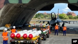台湾军队士兵站在F16V战机前,准备进行装载美制AGM-84鱼叉反舰导弹及AIM-120和AIM-9空空导弹的训练。(2022年9月16日)