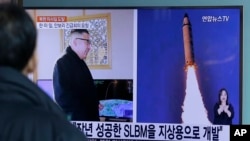 在韩国首尔火车站，有人观看电视新闻显示的朝鲜报纸刊登的照片，图片上有朝鲜领导人金正恩和朝鲜发射导弹的景象。（2017年2月13日资料图）