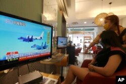 2022年8月4日，在台湾台北的一家美容院，一名顾客和一名工作人员在观看关于最近中国大陆和台湾之间紧张关系的新闻报道。