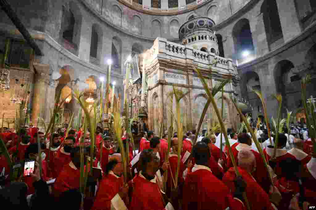 Roman Catholic clergy carry palm branches as they circle the aedicule during the Palm Sunday procession at the Church of the Holy Sepulchre in Jerusalem's Old City.
