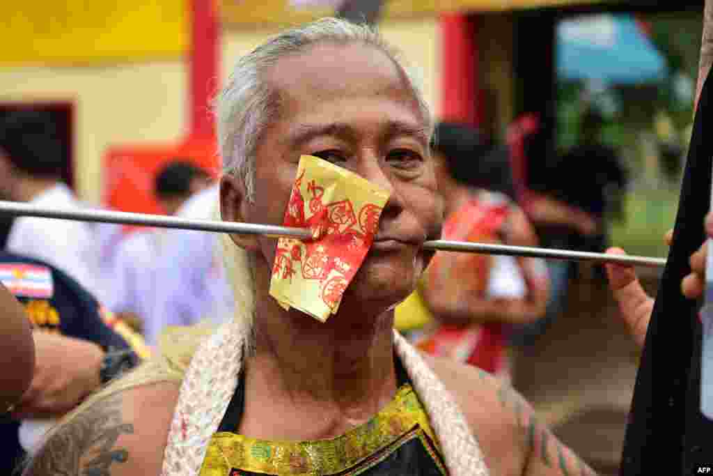 A man looks on after having his cheeks impaled as he takes part in an annual parade in honor of the goddess of the Gow Lengchi Shrine, a traditional Chinese-style shrine in Narathiwat town, in Thailand's southern Narathiwat province.