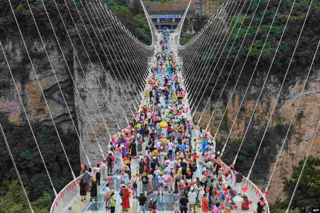People walk on a glass-bottomed skywalk in Zhangjiajie, in China's central Hunan province, June 20, 2021.