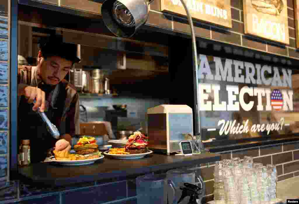 Juru masak J.S. Burgers Café, Yasuhito Fukui, mempersiapkan Mr. dan Mrs. Burger yang mewakili kandidat kepresidenan AS Hillary Clinton dan Donald Trump, di warung hamburger di Tokyo, Jepang. Bahan-bahan burger yang mewakili Clinton mencerminkan tradisi khas Chicago, sementara burger Trump mencerminkan tradisi khas New York.