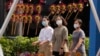 戴着口罩的行人走过北京街头一个售卖传统风车玩具的商铺。（2022年9月13日）