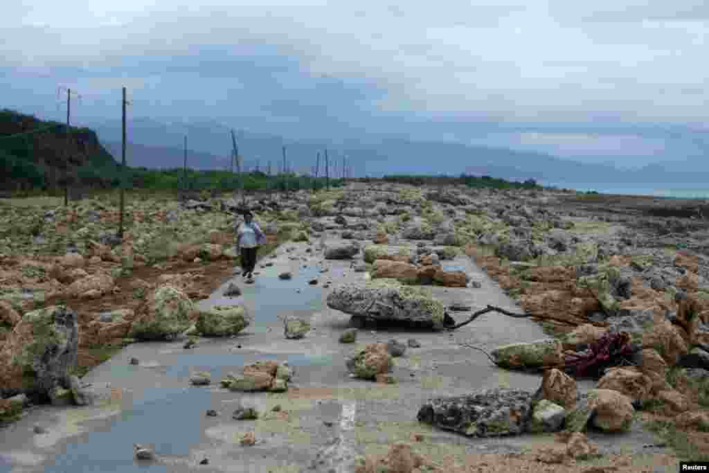 A woman walks on a highway blocked by rocks after the passage of hurricane Matthew on the coast of Guantanamo province, Cuba.