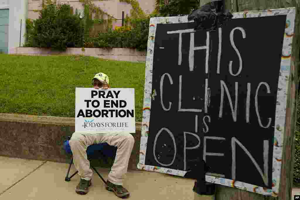 An anti-abortion supporter sits behind a sign that advises the Jackson Women's Health Organization clinic is still open in Jackson, Mississippi. A state law banning most abortions means the clinic will close at the end of business Wednesday and the state law will take effect Thursday.
