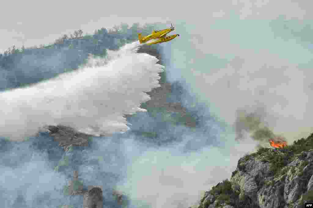 A firefighting plane drops water during fire containment operations near Artesa de Segre, in Catalonia, as Spain remained in the grip of an exceptional heat wave.