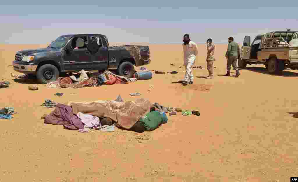 A handout picture provided by the Libya Ambulance Service shows rescuers recovering bodies of migrants found in the Libyan desert, in the southeastern region of Kufra near the border with Chad. Twenty people were found dead in the desert following a vehicle breakdown near the border with Chad.