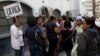 Una mujer de la tercera edad se identifica como la última de la fila para hacer compras en un supermercado del gobierno en Caracas.