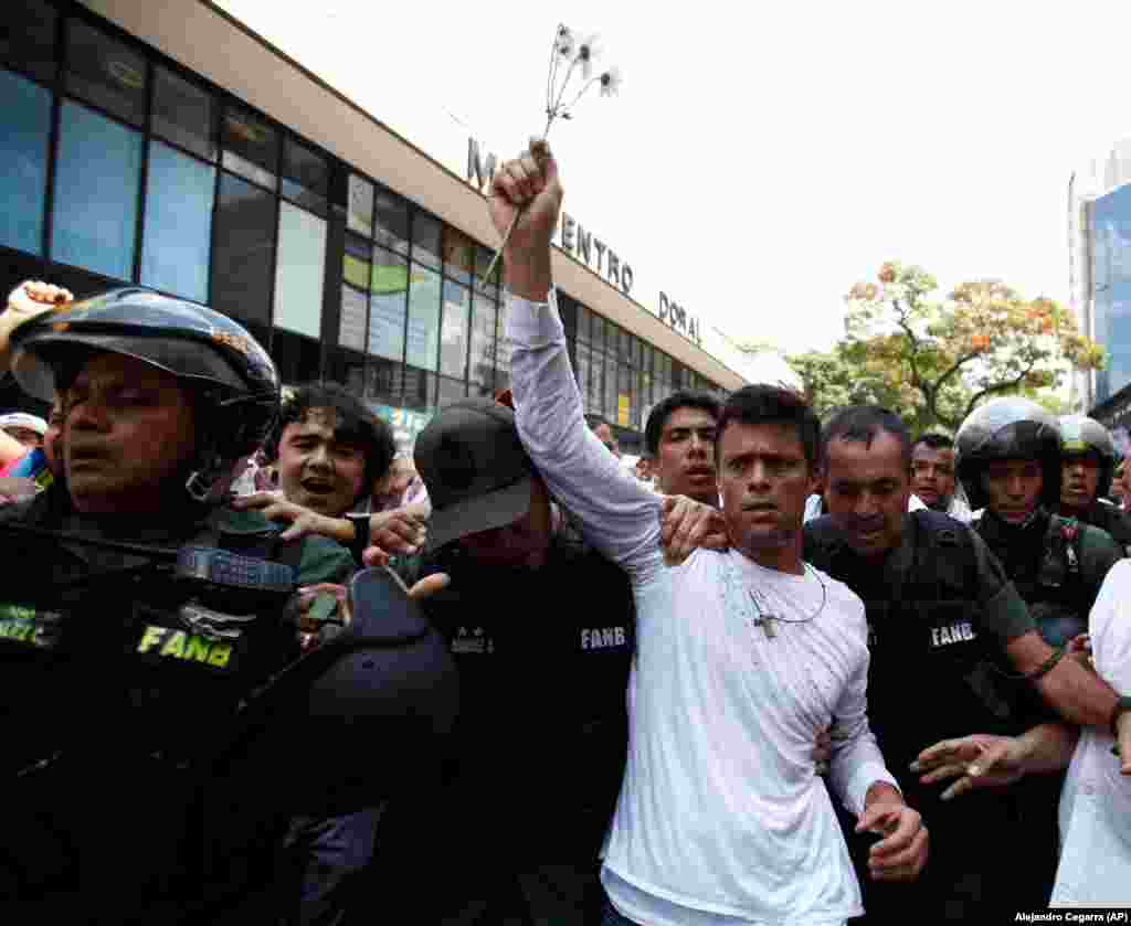 O líder da oposição, Leopoldo López, vestido de branco, é levado em custódia pela Guarda Nacional Bolivariana, em Caracas, Venezuela, terça-feira, 18 de Fevereiro, 2014.