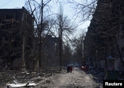 Stanovnici hodaju pored zgrada uništenih u ruskom bombardovanju, u Marijupolju, Ukraina, 18. marta 2022.
