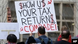 Tax FILE - A protester in Seattle holds a sign during a rally that reads "Show us your tax returns, Comrade" in reference to calls for President Donald Trump to release his tax returns and his alleged ties to Russia, April 15, 2017.