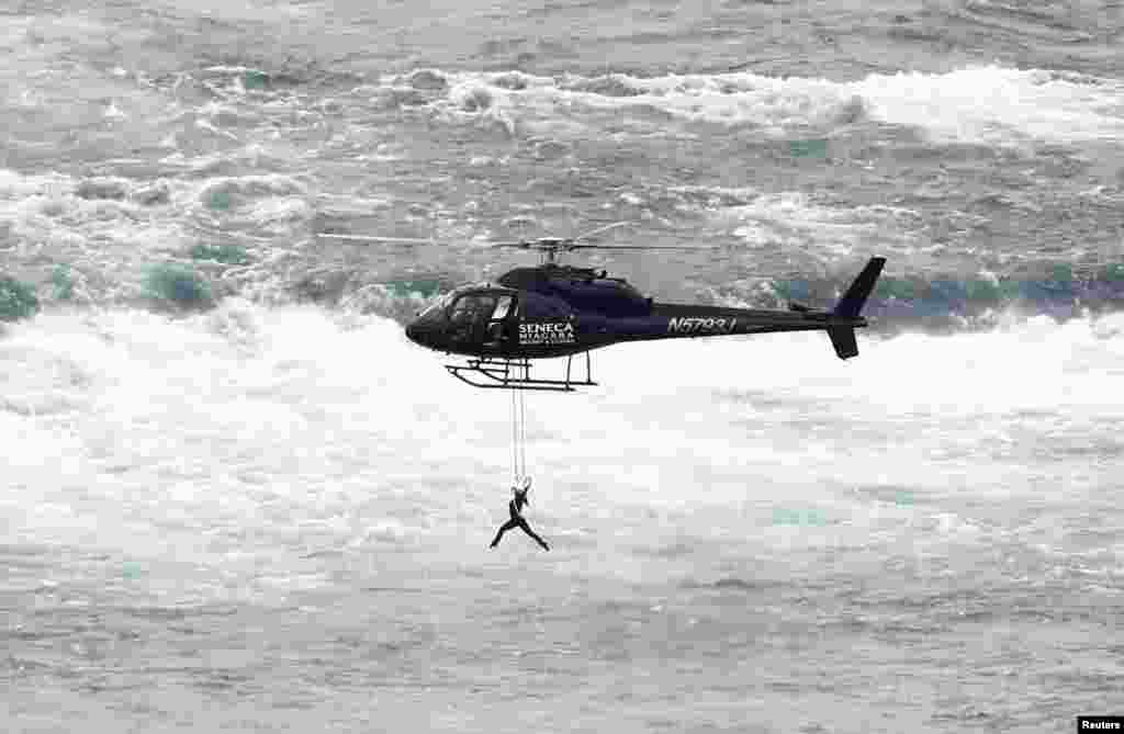 美国空中飞人埃伦迪拉·瓦伦达(Erendira Wallenda) 吊在直升机上表演杂技,在加拿大一侧飞越尼亚加拉瀑布(6月17日)。她的丈夫尼克·瓦伦达2012年6月15日走钢丝成功穿越尼亚加拉瀑布,成为史上这么做的第一人。