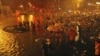 救援人员和北京居民7月21日在大雨中站在一辆被从水淹的街道上拖出的汽车旁