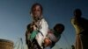 FILE - A young girl carries her sister through a cornfield in Masongo village outside Lilongwe, Malawi, May 13, 2008. 