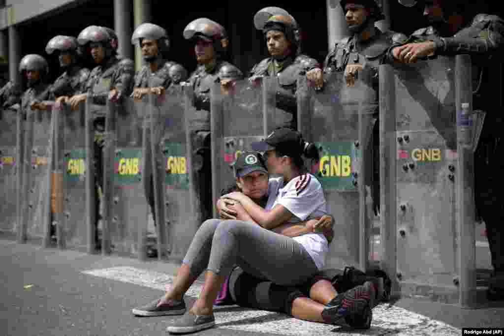 Mulheres abraçam-se na frente da Guarda Nacional Bolivariana, em Caracas, Venezuela, quarta-feira, Fevereiro 19, 2014.