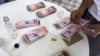 Una mesera cuenta bolívares con los que se pagaron un almuerzo para cuatro personas en un restaurante de Caracas.