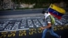 Un manifestante llevando una bandera venezolana corre junto a una lista de las víctimas de la violencia durante protestas contra el gobierno del presidente de Venezuela, Nicolás Maduro en Caracas. Junio 12 de 2017.