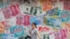 A woman walks by a money exchange shop decorated with different countries currency banknotes at Central, a business district in Hong Kong, Tuesday, Aug. 6, 2019. 