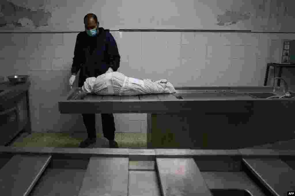 A Palestinian man stands by the body of Menna Shreir, 3, at a morgue in Gaza City, after she died of her injuries following an Israeli airstrike on her home, which also killed her parents.