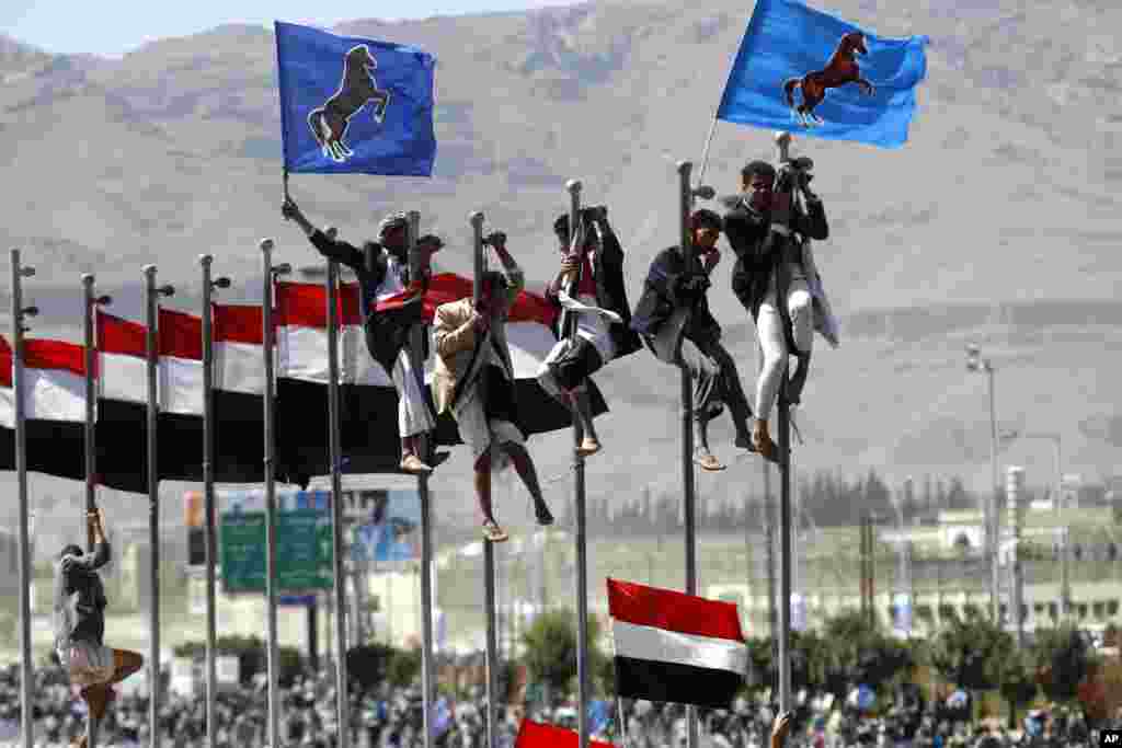 Para pendukung mantan Presiden Yaman, Ali Abdullah Saleh memanjat tiang bendera saat berlangsungnya peringatan ulang tahun serah terima kekuasaannya di Sana'a, Yaman.